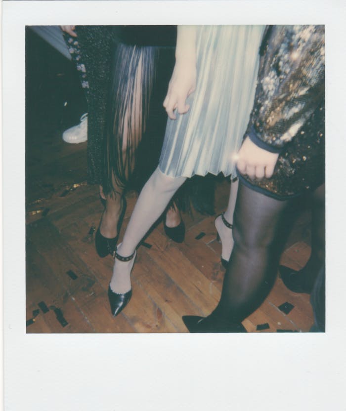 Home Stylish women in chic outfits and heels at a lively indoor party.